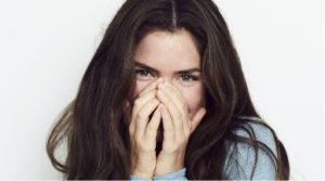 Woman smiling while covering her mouth