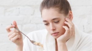 Woman staring at the tablespoon she is holding