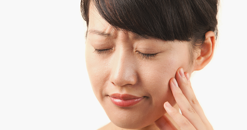 Young woman holding her jaw in obvious pain