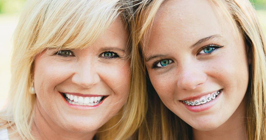 caucasian mother daughter heads together smiling looking into camera