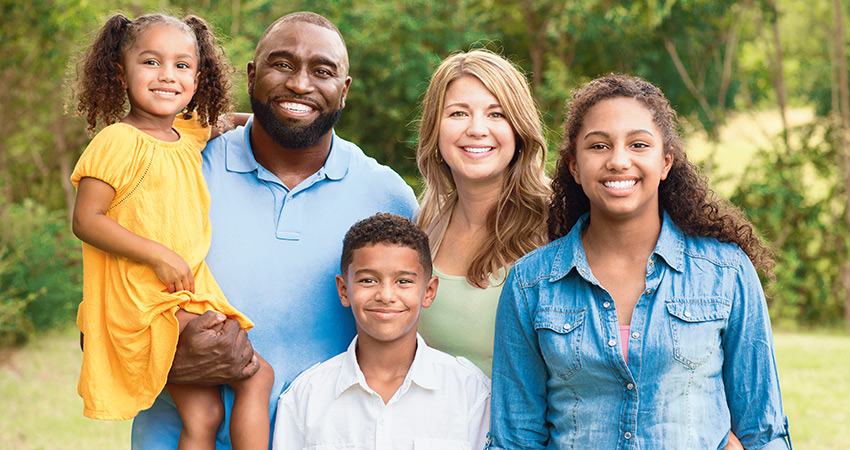 mixed-race family group shot smiling at camera summer