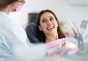 Female patient smiling while facing her dentist