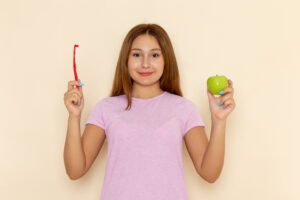 front-view-young-attractive-female-pink-t-shirt-blue-jeans-holding-apple-toothbrush