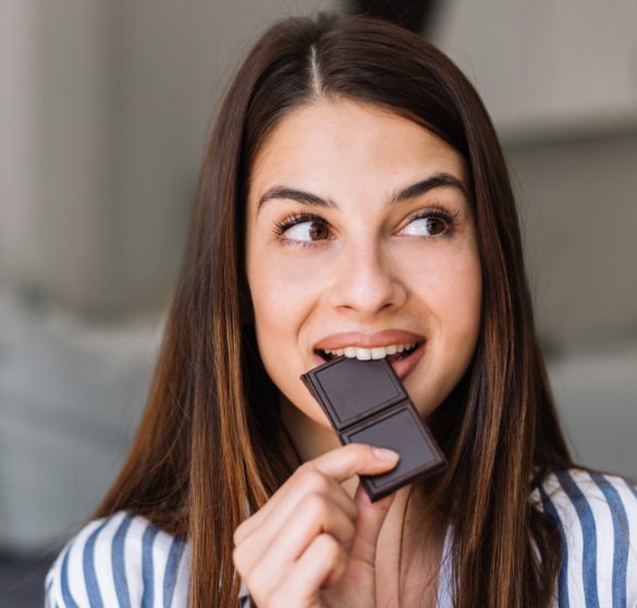 Woman eating a piece of chocolate.